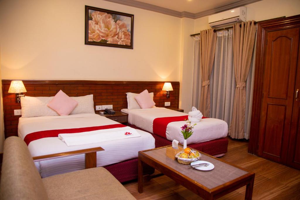 una camera d'albergo con due letti e un divano di Hotel The White Lotus View Pvt Ltd a Bhairāhawā