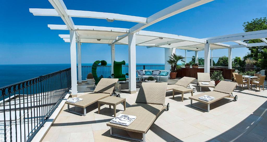 a patio with chairs and a pergola and the ocean at Hotel Posillipo in Gabicce Mare