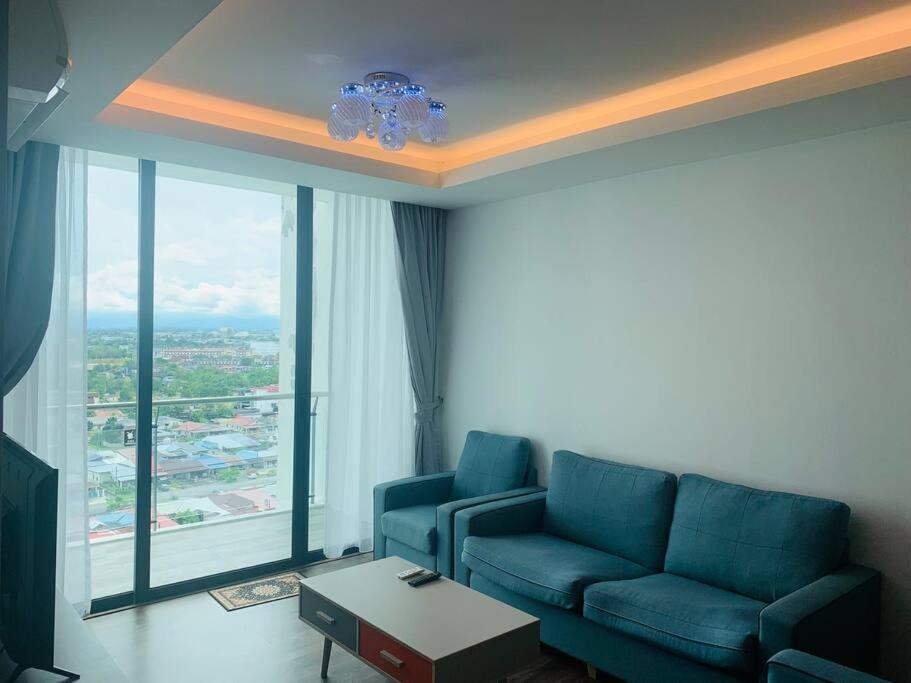 Una sala de estar con un sofá azul y una ventana grande. en Rohani Jazz Suites 4 @ Vivacity Megamall, en Kuching