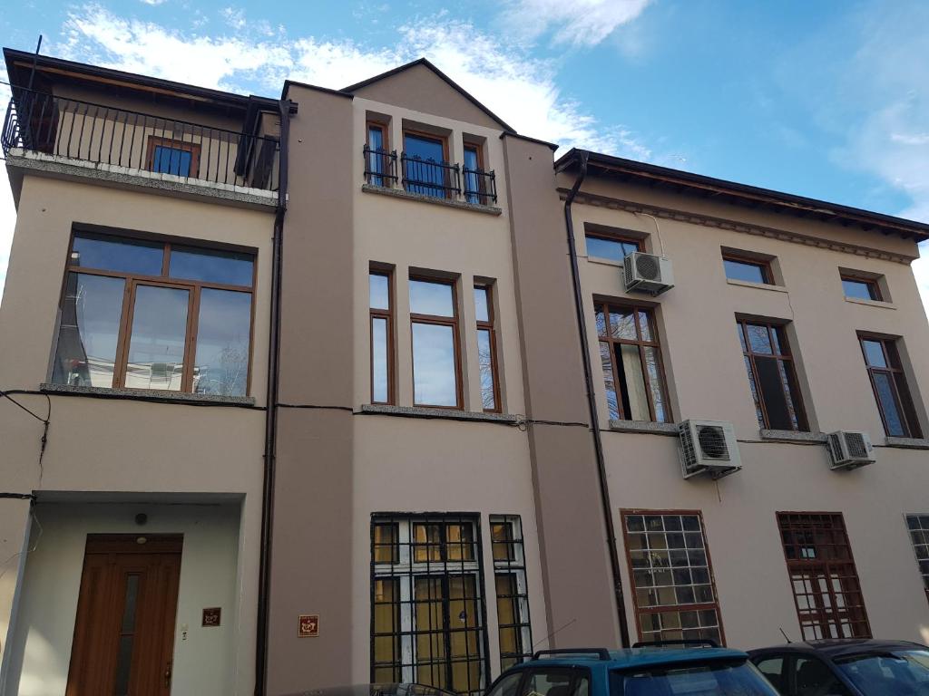 un grand bâtiment blanc avec des fenêtres et des voitures garées devant dans l'établissement The Old House guest rooms and apartament, à Plovdiv