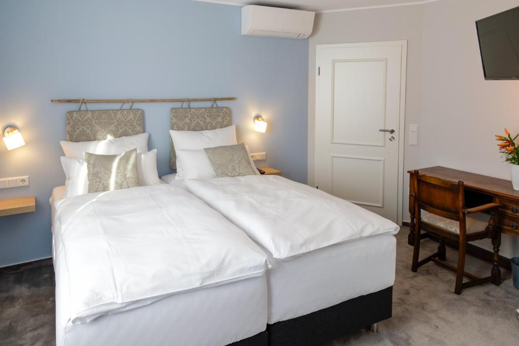 a bedroom with a large white bed and a desk at Hotel Brasserie Chaussee in Seeheim-Jugenheim