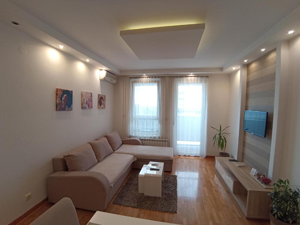 uma sala de estar com um sofá e uma televisão em Apartment Tifani em Belgrado