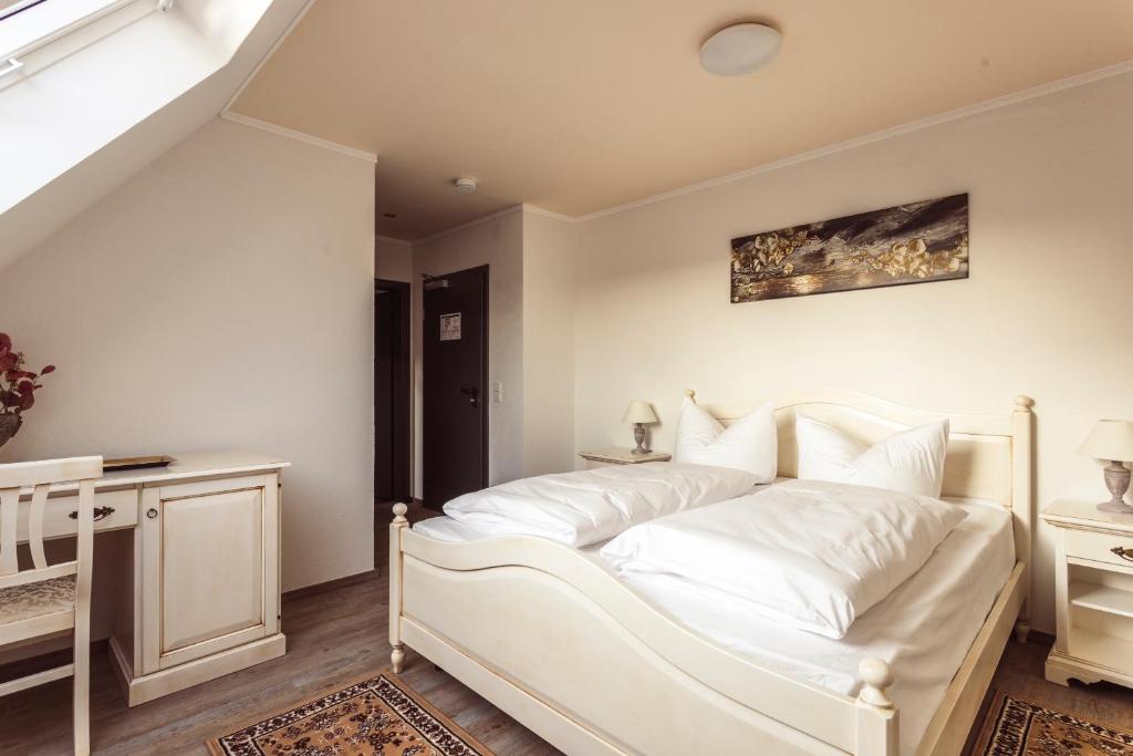 a white bedroom with a white bed and a table at Hotel Roma in Kehl am Rhein