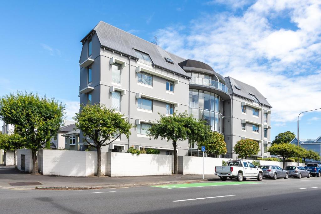 um prédio de apartamentos branco com carros estacionados em frente em Riverside 1-Bed Apt - in the heart of the city em Christchurch