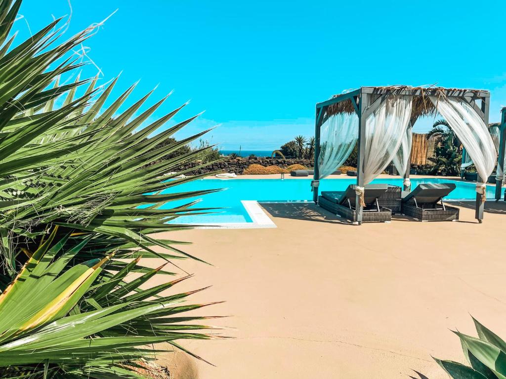 a pool with a gazebo and chairs on the beach at Etherea - I Dammusini di Pantelleria in Pantelleria
