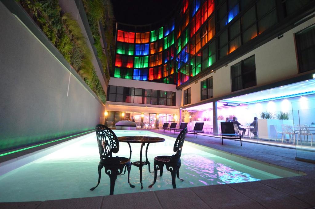 un edificio con mesa y sillas frente a una piscina en Holiday Inn Dijon Toison D'or, an IHG Hotel, en Dijon