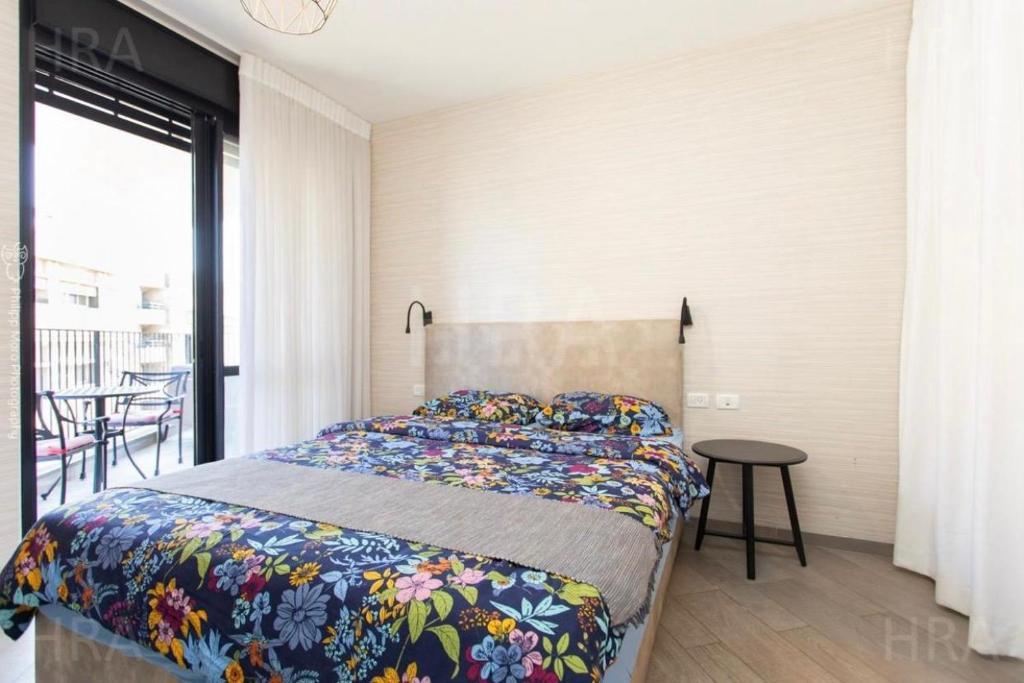 a bedroom with a bed and a table and a balcony at Beach Apartments in Haifa