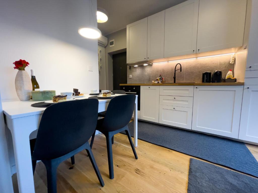 uma cozinha com armários brancos e uma mesa e cadeiras em URBAN APARTMENTS STUDIO No 3A Chorzów Katowice, FREE PRIVATE PARKING em Chorzów
