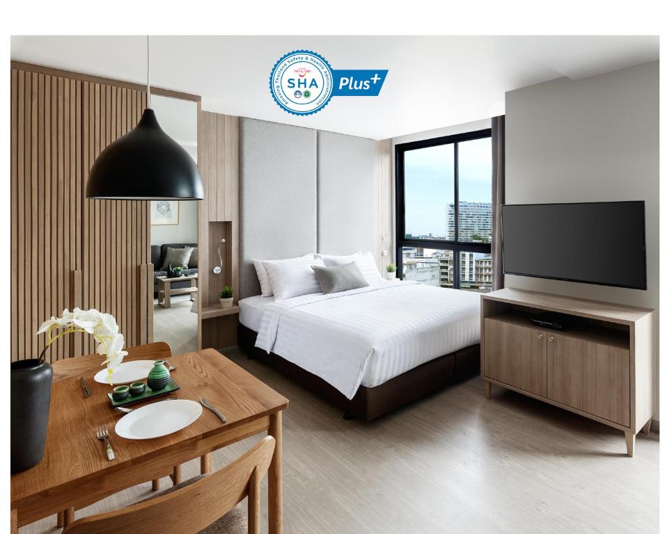 een hotelkamer met een bed, een bureau en een televisie bij Madera Residence Sriracha in Si Racha