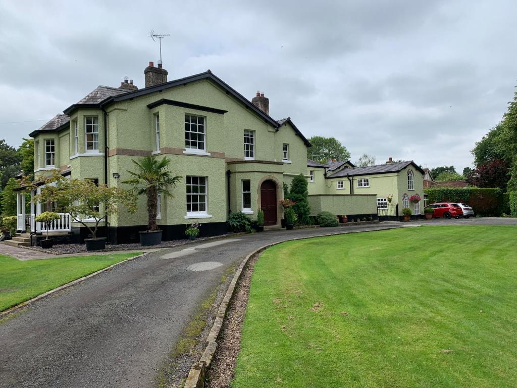 a large green house with a road in front of it at Ground floor apartment in The Coach House in Hartford