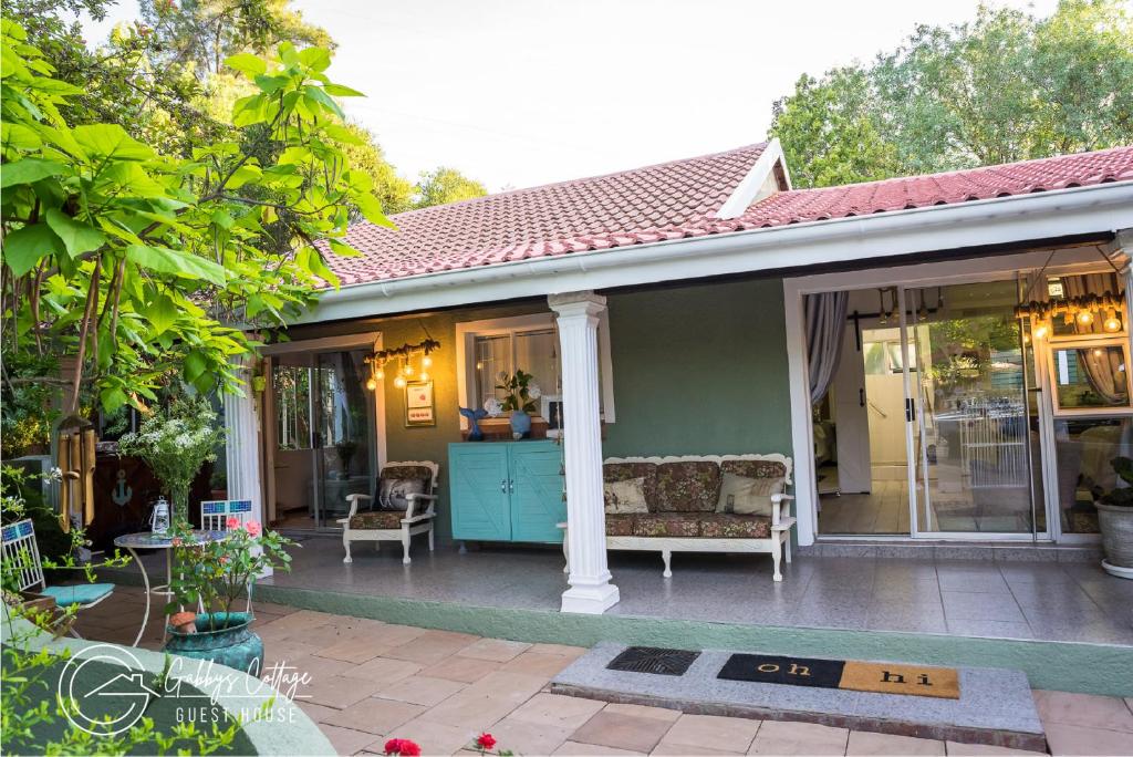 a house with a porch with a couch and chairs at Gabbys Cottage Guesthouse in Bloemfontein
