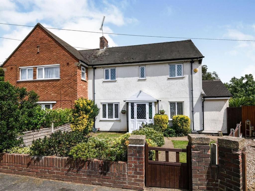 una casa bianca con una recinzione davanti di Specious 3bed property with parking & large garden ad Aveley