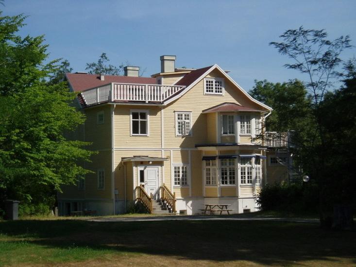 Una gran casa amarilla con una terraza encima. en Liljenborg en Jämshög