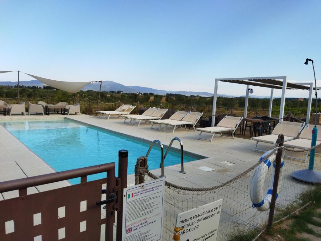 a swimming pool with lounge chairs and a fence at Azienda Agrituristica Le Betulle in Riotorto