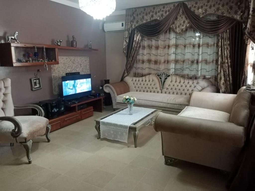 a living room with a couch and a tv at Maison koukou in Boumhel El Bassatine