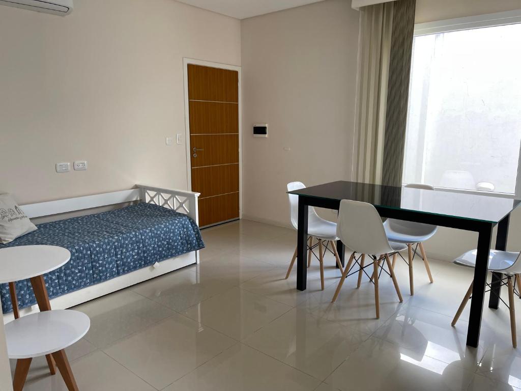 een slaapkamer met een bed en een tafel en stoelen bij Dpto Moderno - 1 dormitorio, hasta 4 personas in Tandil