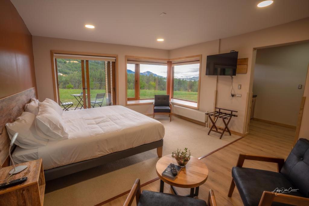 a bedroom with a large bed and a living room at Calafate Apart Hotel in Coihaique