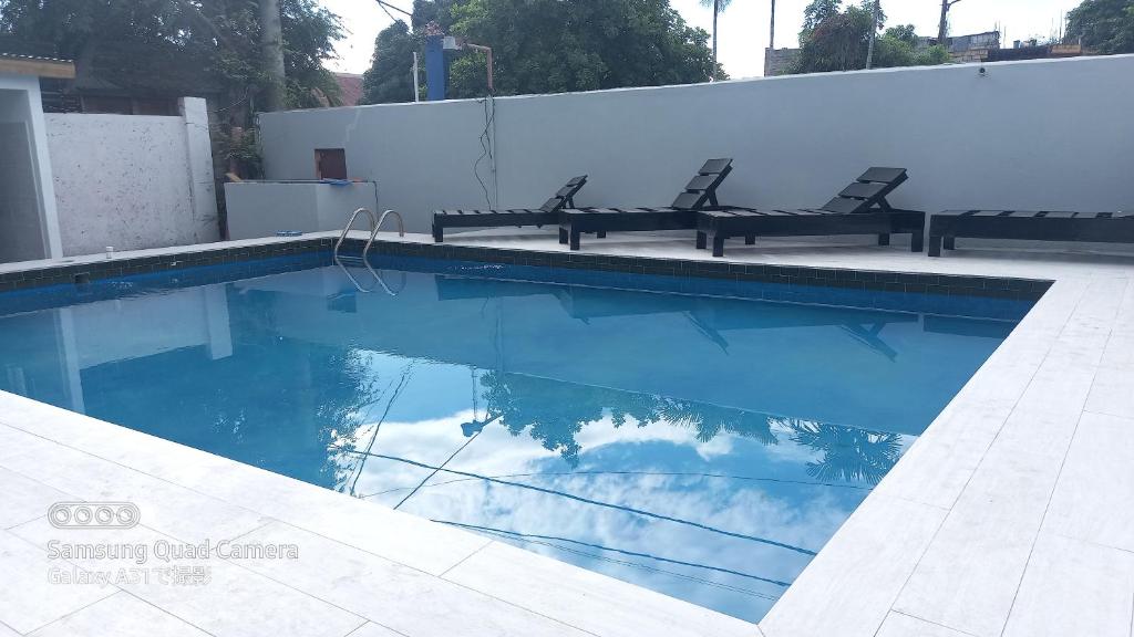 a swimming pool with two chairs and the sky in the water at Labrish Guest House in Kingston
