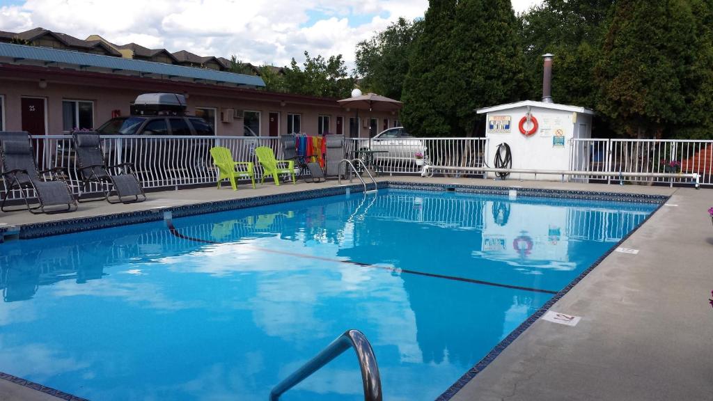 a large swimming pool with chairs and a building at Swiss Sunset Inn in Penticton