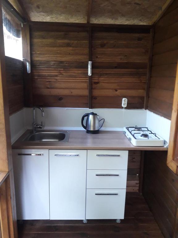 una pequeña cocina con armarios blancos y fregadero en Bungalow Halil en Cıralı