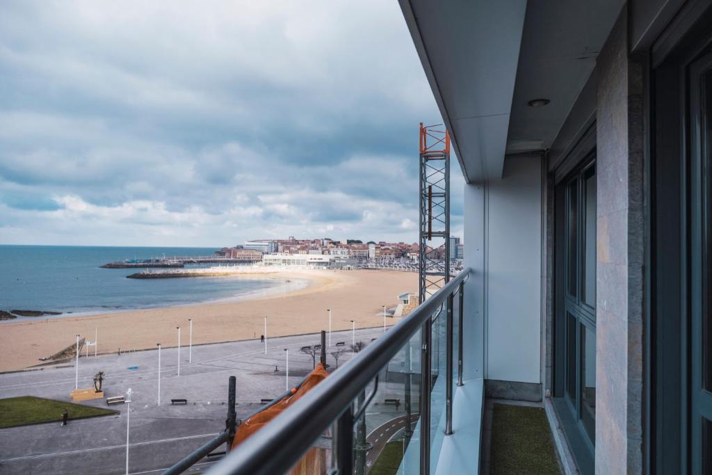 a balcony with a view of a beach and the ocean at EL SEXTO DE LA PLAYA + PARKING GRATIS in Gijón