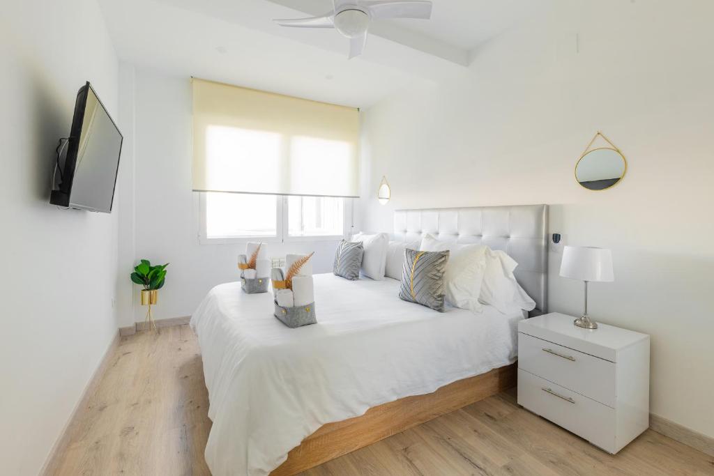 Dormitorio blanco con cama blanca y TV en SWEET DREAMS APARTMENT NEAR PUERTA DEL SOL, en Madrid