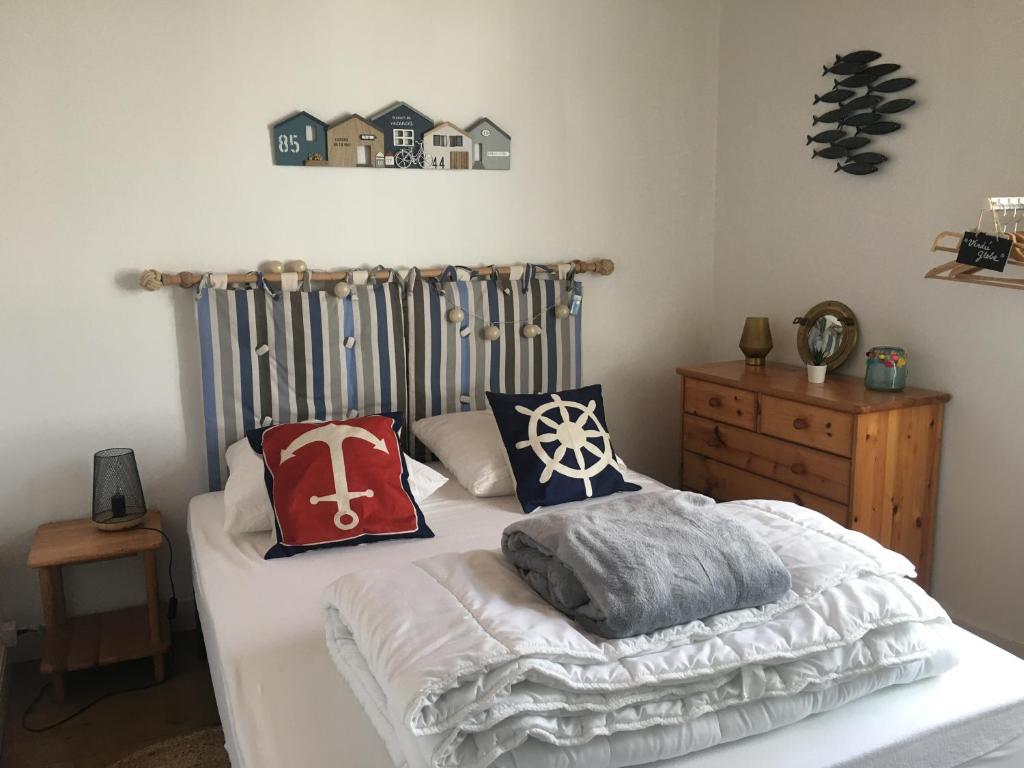 ein Bett mit Kissen darauf im Schlafzimmer in der Unterkunft Maison de pays à 2 pas de la mer et du centre in La Tranche-sur-Mer