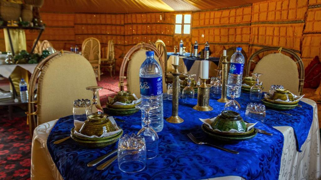 un tavolo con una tovaglia blu e bottiglie sopra di Atta Desert Camp a El Gouera