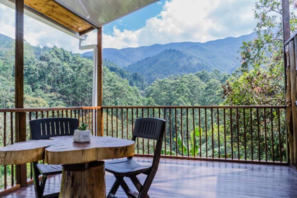 una mesa y sillas en una terraza con vistas a las montañas en Cabaña campestre cerca a Ecoparque El Salado, Envigado., en Envigado