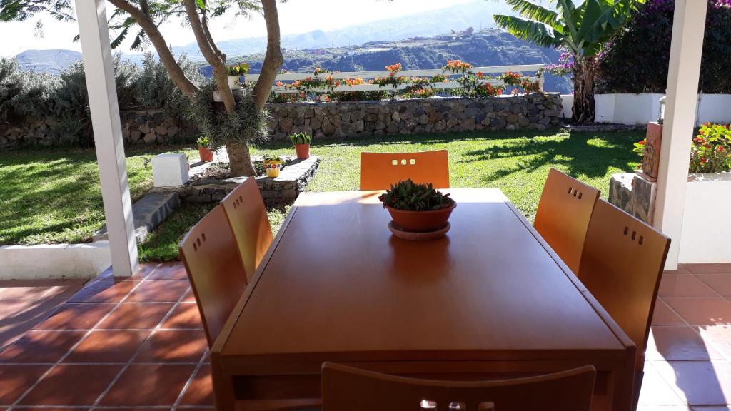 una mesa de madera y sillas en un patio con vistas en Casa cueva Bandama con jacuzzi en Tafira