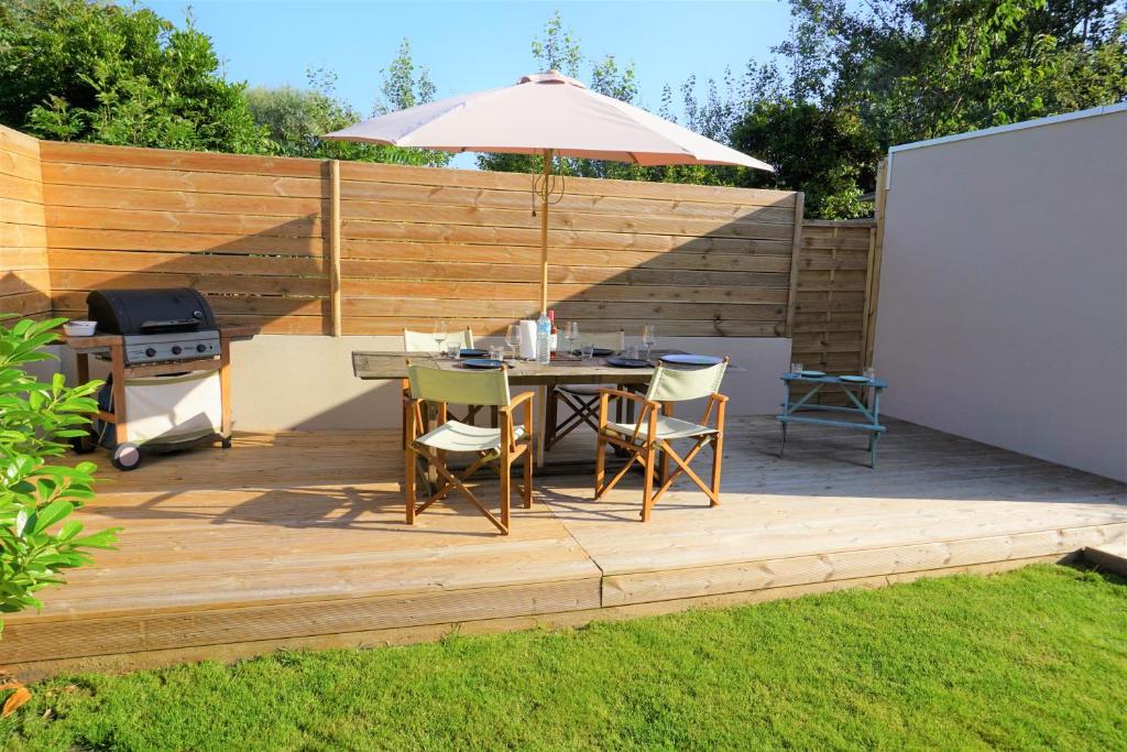 - une terrasse avec une table, un parasol et un grill dans l'établissement L'Escapade - Maison - Spacieuse - Jardin - Plage, à Zuydcoote