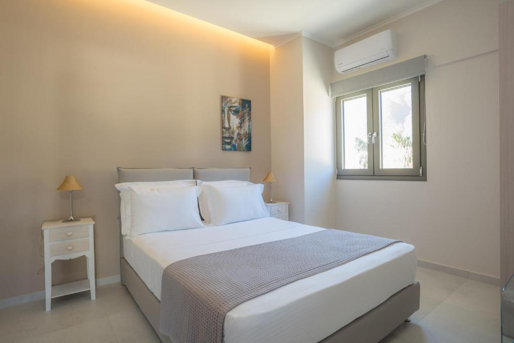 a white bedroom with a bed and a window at Apollonian Luxury Apartments in Vasiliki