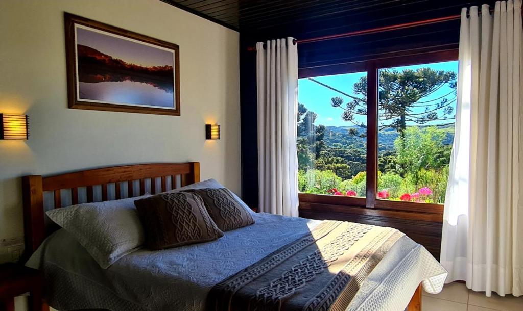 a bedroom with a bed and a large window at Pousada Rural Vista Alegre in Bom Jardim da Serra