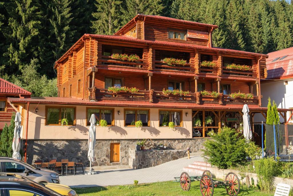 a large wooden building with tables and chairs in front of it at Pensiunea Moeciu Casa Wiarusti in Moieciu de Sus
