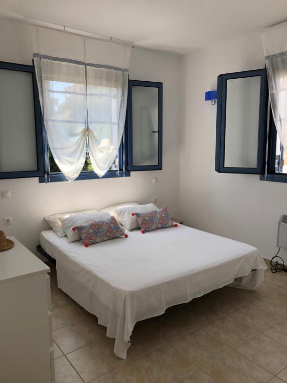 1 dormitorio con 1 cama blanca grande y ventanas en Villa Thea - The View 2nd floor, en Áno Yerakaríon