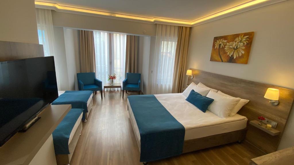 a hotel room with a bed and a flat screen tv at Pelit Troya Hotel in Çanakkale