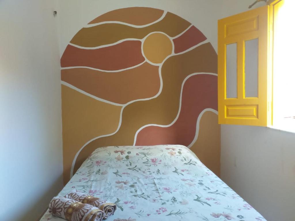 1 dormitorio con 1 cama con una pintura en la pared en Casa Relva Suítes, en Lençóis