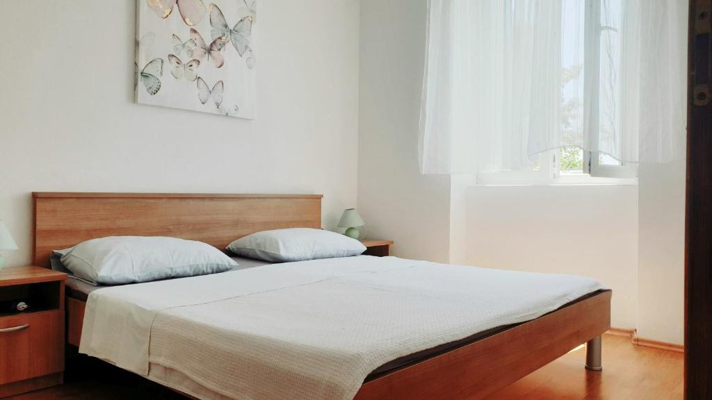1 dormitorio con 1 cama con sábanas blancas y ventana en Apartmani Paron Šime, en Seline