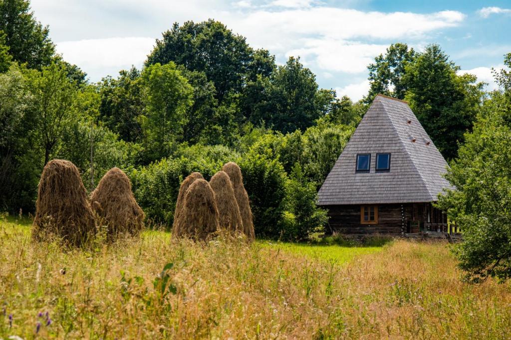 una casa vieja en un campo con pilas de heno en Breb 148 Local Food&Garden, Guesthouse, en Breb