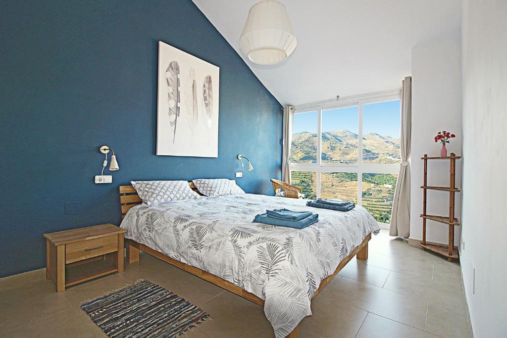 sypialnia z łóżkiem i niebieską ścianą w obiekcie Casa Indigo w Almuñécar