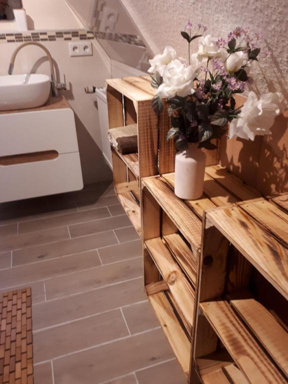 een badkamer met een houten kast met een vaas met bloemen erop bij FerienhausWeseby in Hürup