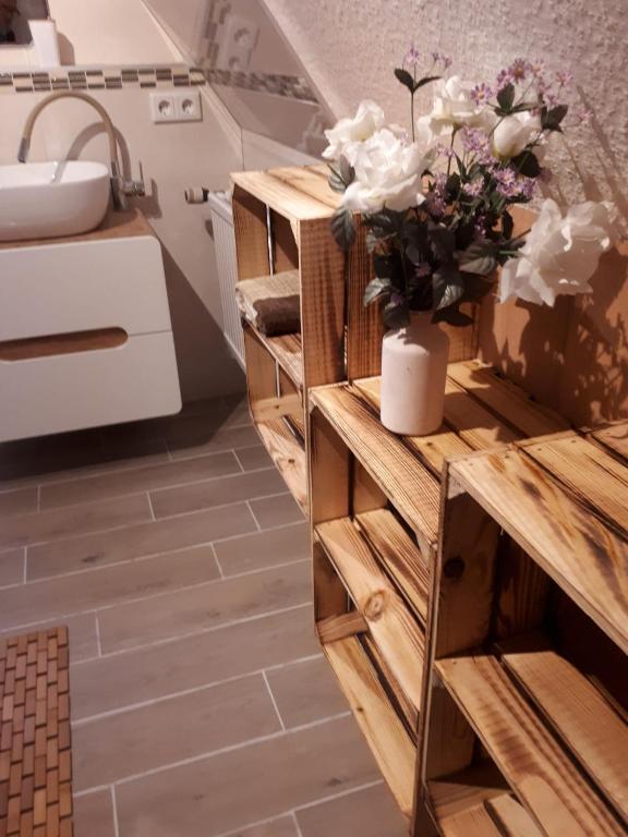 a bathroom with a wooden cabinet with a vase of flowers on it at FerienhausWeseby in Hürup