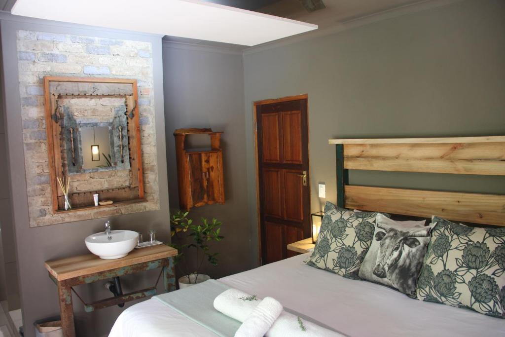 - une chambre avec un lit, un lavabo et un miroir dans l'établissement Green Pascua Bed and Breakfast, à Roodepoort