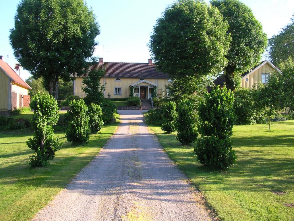 uma entrada arborizada que leva a uma casa em Sjöbredareds Gård em Hökerum