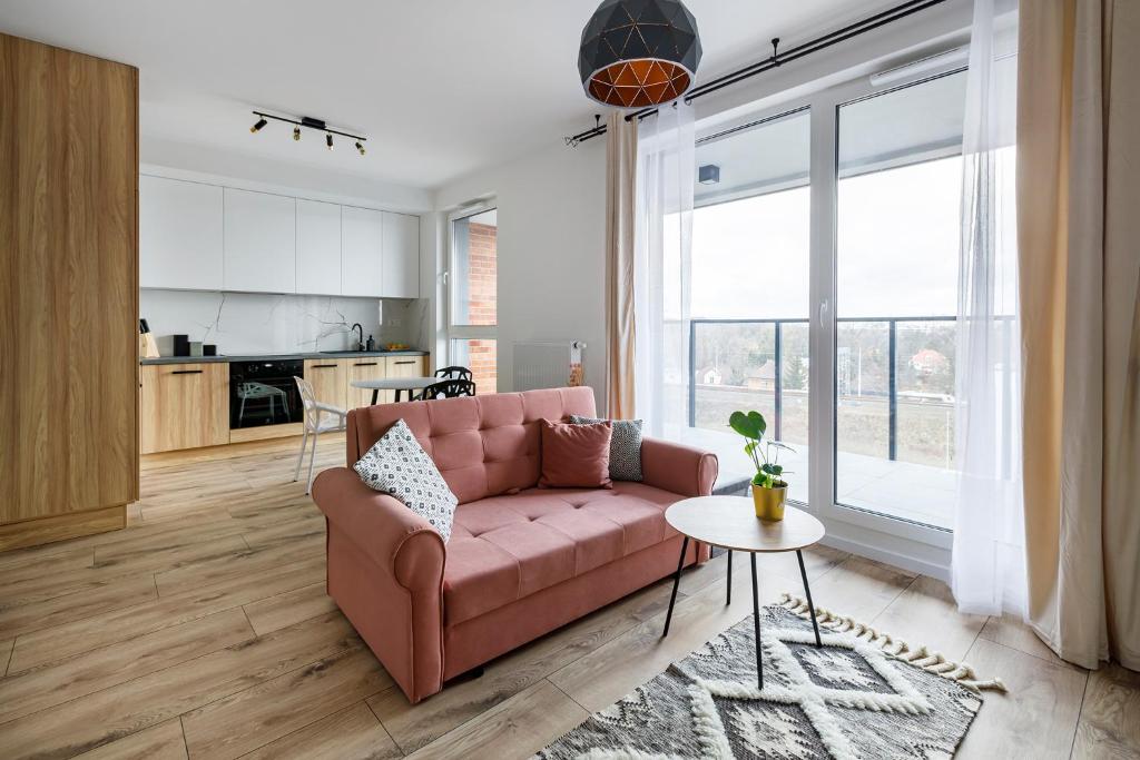 sala de estar con sofá rosa y cocina en Homewell Apartments Goplana en Poznan