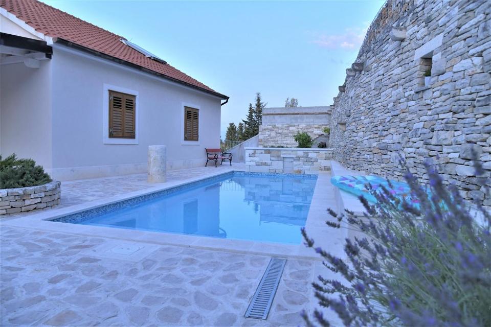 una piscina frente a un edificio de piedra en Villa Aries, en Supetar