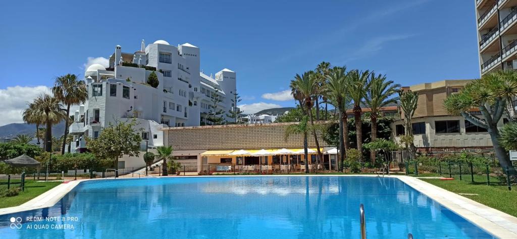 una grande piscina blu di fronte a un edificio di Torremolinos 1ª linea playa a Torremolinos