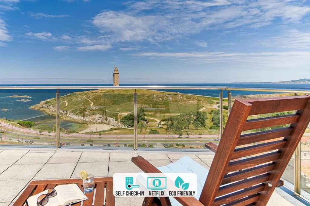 a table and a chair on a balcony with a lighthouse at Blue Ocean Penthouse in A Coruña