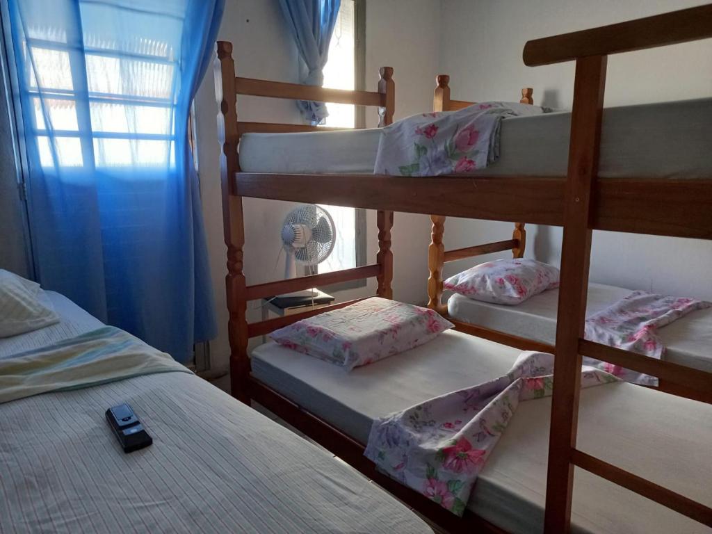 een slaapkamer met 3 stapelbedden en een mobiele telefoon op het bed bij Pousada Alexandrina in Cachoeira Paulista