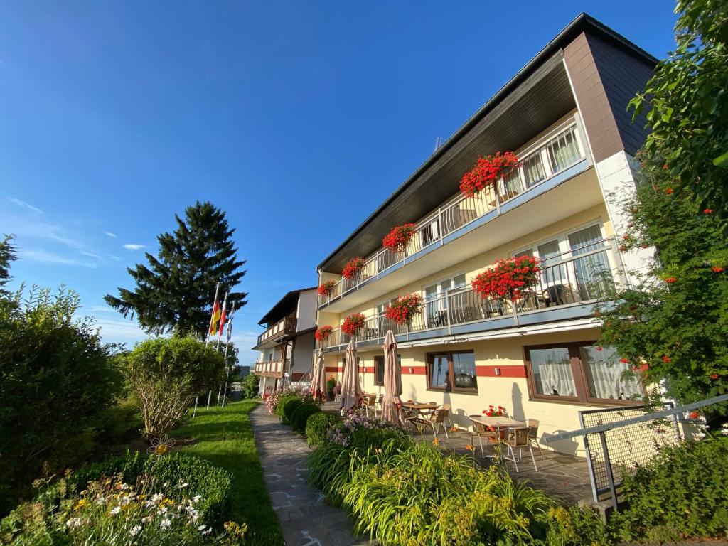 a building with flowers on the balconies and tables at Marias Pension in Falkenstein